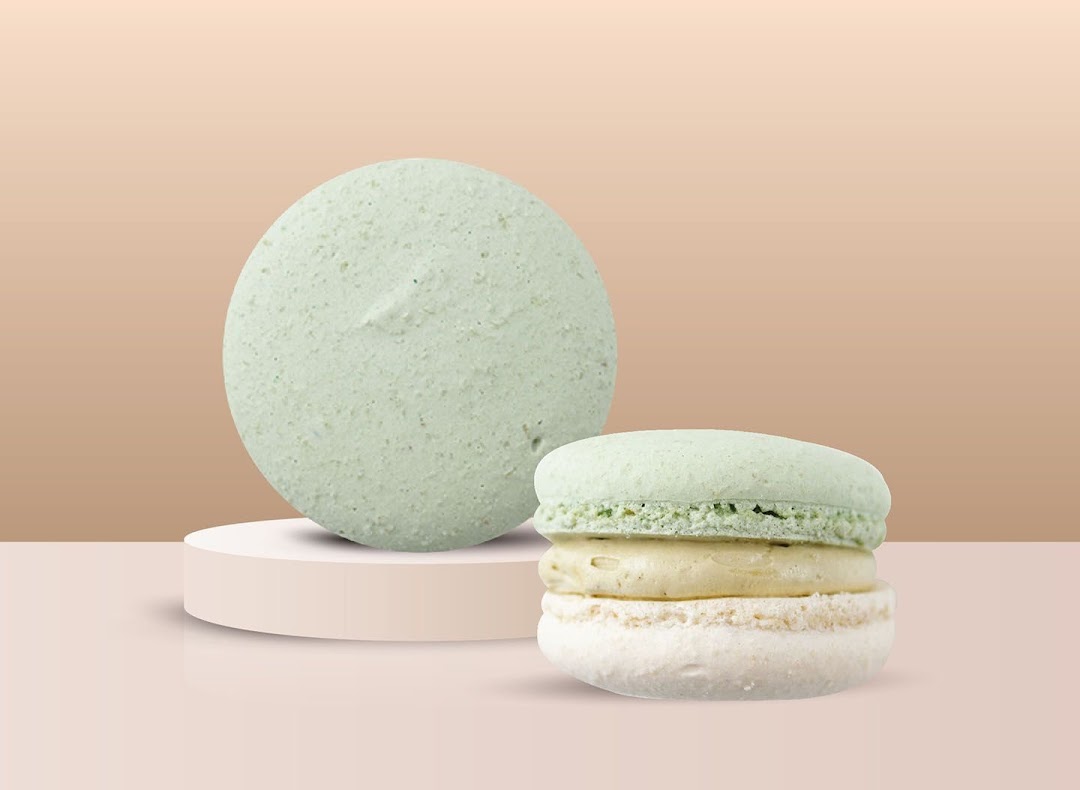 Two light green and white macarons displayed on a minimalist background.