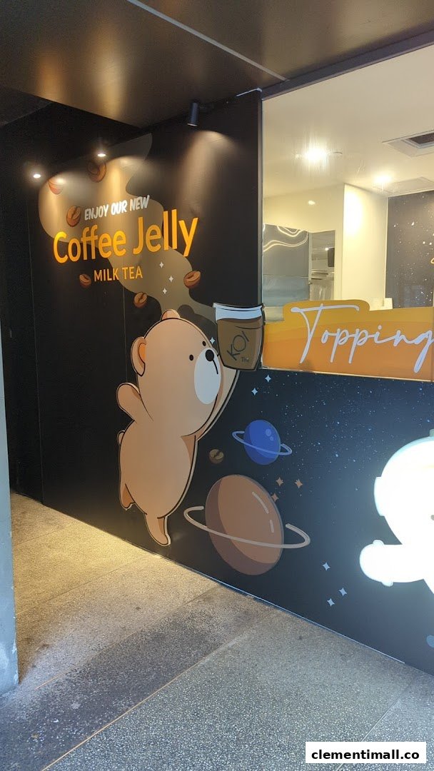 A promotional wall at KOI Thé featuring a cartoon bear and 'Coffee Jelly Milk Tea' advertisement.