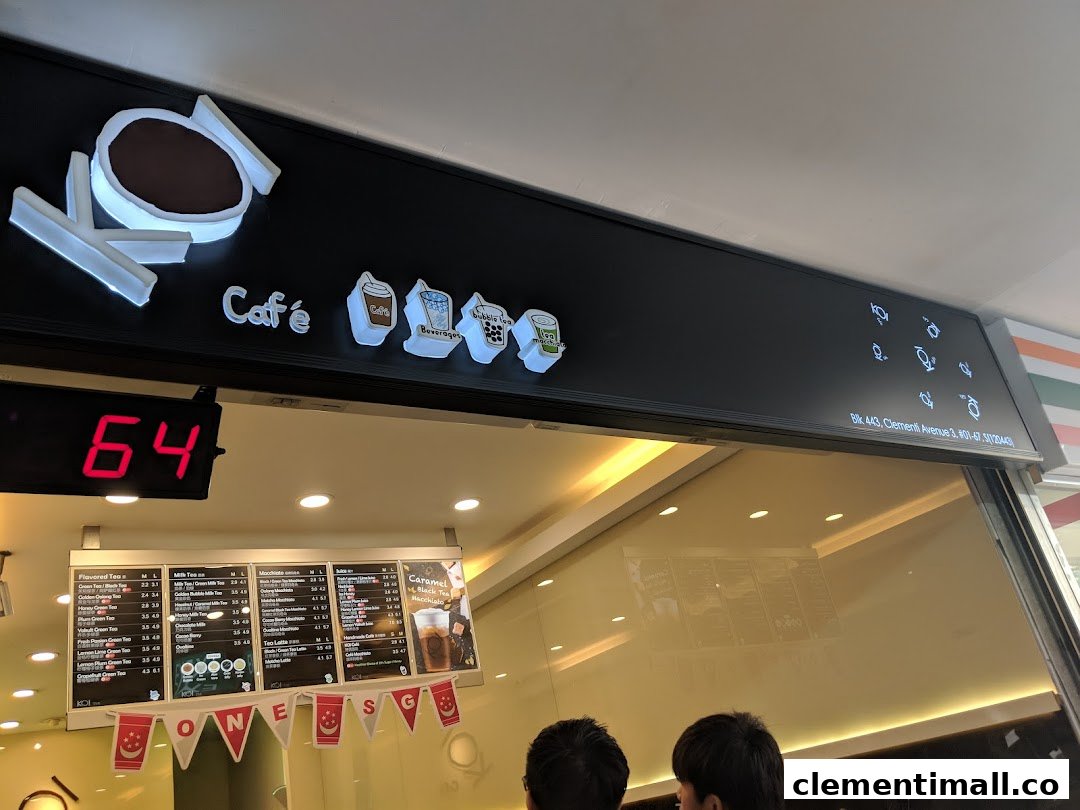 The illuminated KOI Thé shopfront with its distinctive logo, queue number display, and visible menu board.