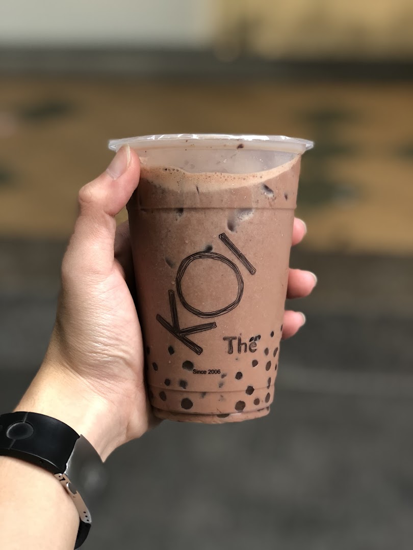 A hand holds a refreshing chocolate-flavored bubble tea from KOI Thé, featuring tapioca pearls.