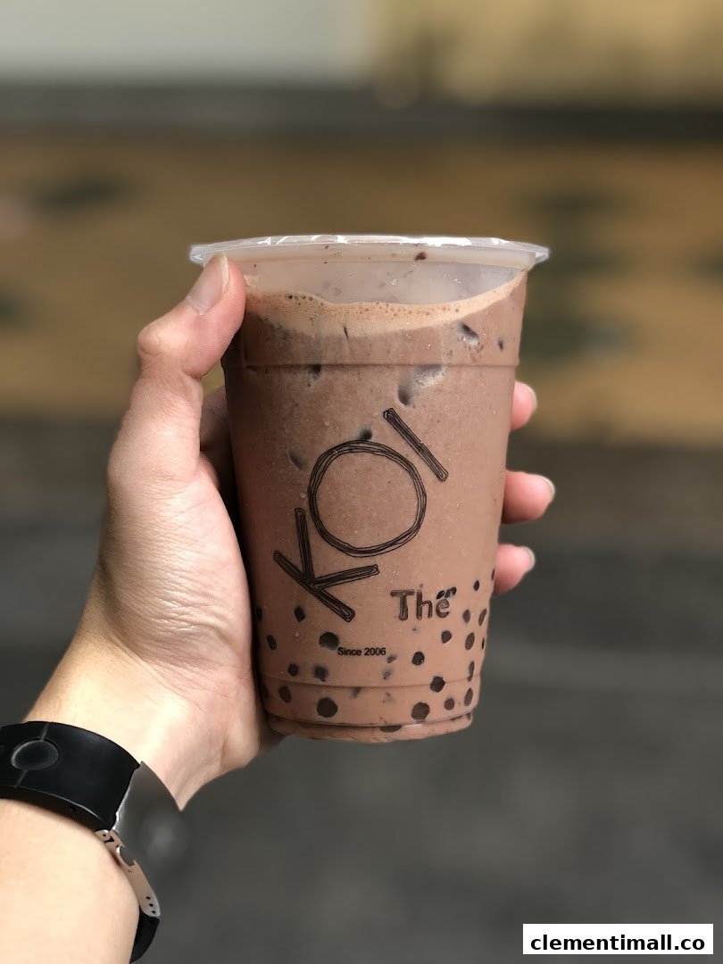 A hand holds a refreshing chocolate-flavored bubble tea from KOI Thé, featuring tapioca pearls.
