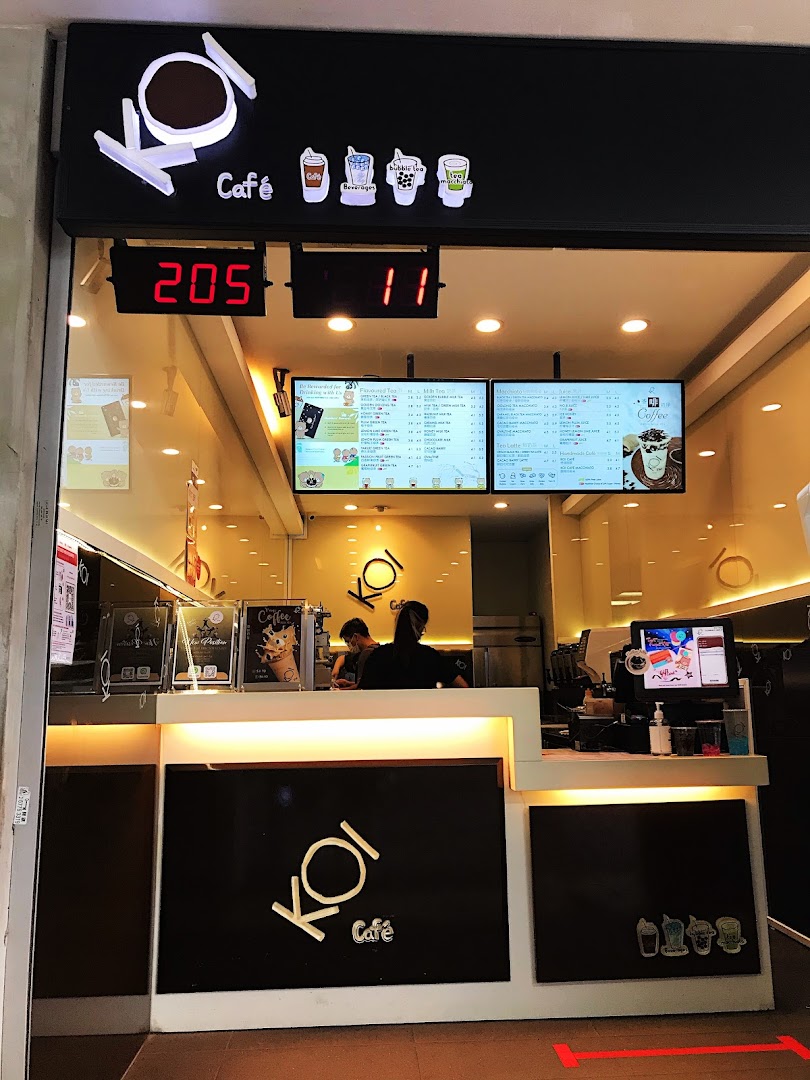 A view of KOI Thé Clementi Mall's counter area with staff and digital menu boards.
