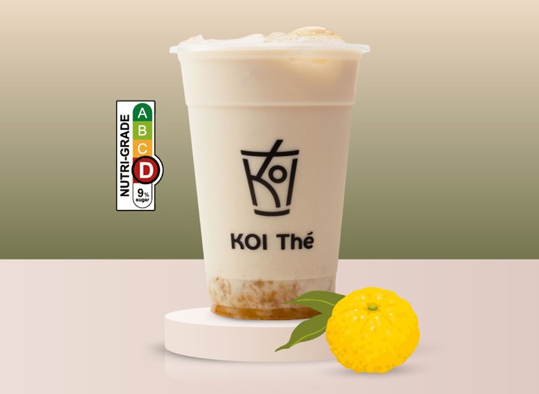 A KOI Thé beverage with a nutri-grade label and a yuzu fruit on a minimalist background.