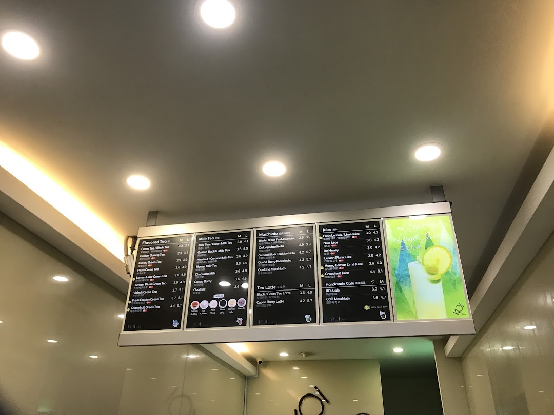 A digital menu board displaying various tea, juice, and macchiato options with prices at KOI Thé.