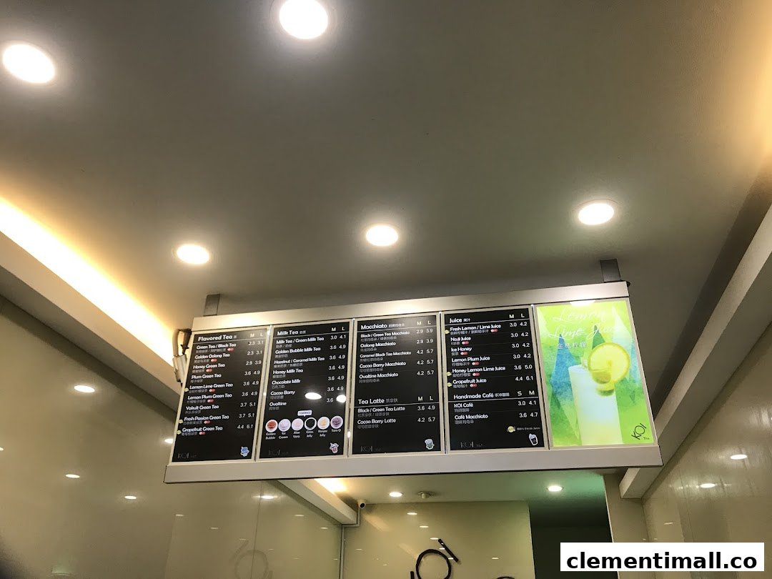 A digital menu board displaying various tea, juice, and macchiato options with prices at KOI Thé.
