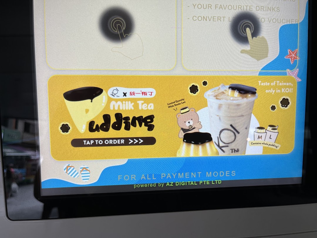 Digital screen at KOI Thé promoting Milk Tea Pudding, featuring ordering options and loyalty program details.