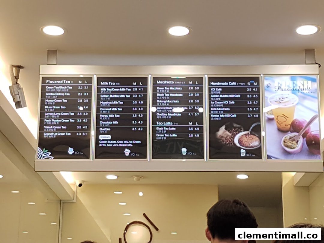 A brightly lit menu board displaying various bubble tea and coffee options at KOI Thé.