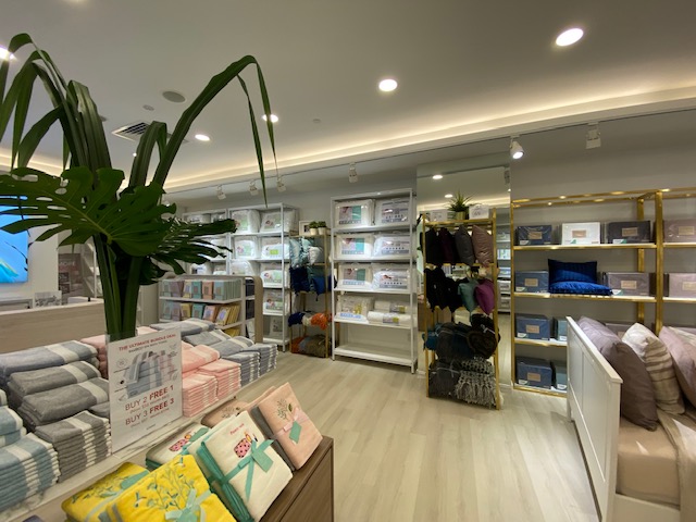 Interior view of KOMME, a home goods store, showcasing bedding, towels, and home essentials with a clean display.