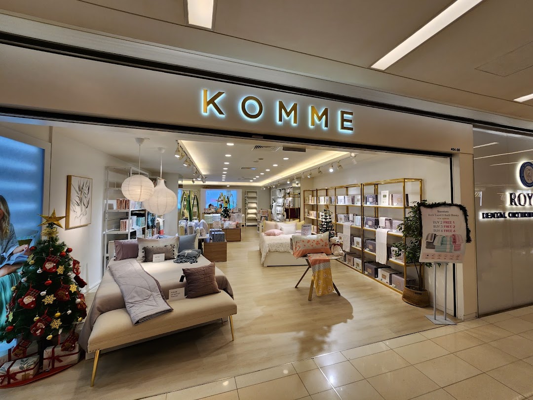 The shop front of KOMME, a home furnishings store, featuring bedding displays and a festive Christmas tree.