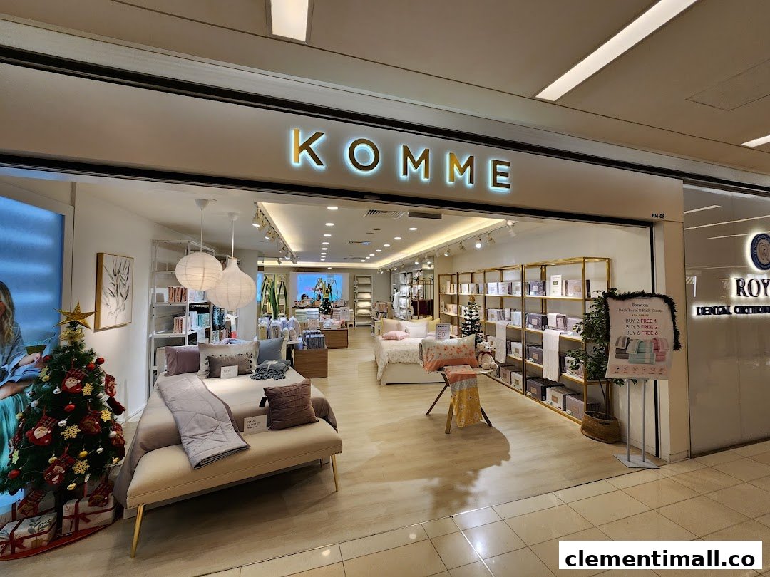 The shop front of KOMME, a home furnishings store, featuring bedding displays and a festive Christmas tree.