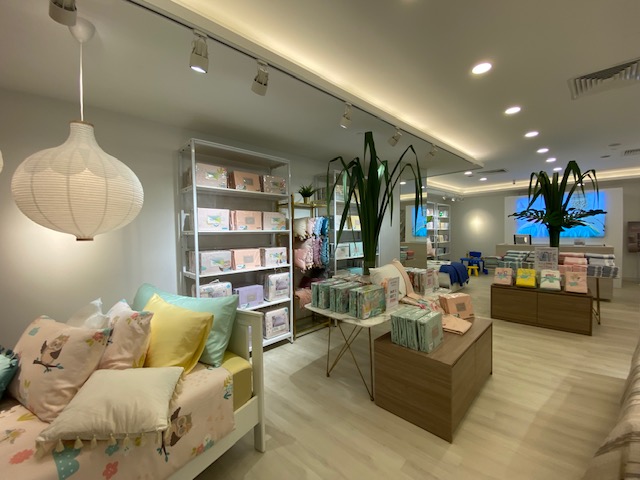 Interior view of KOMME, a home furnishings store, showcasing bedding, pillows, and decorative items in a bright setting.
