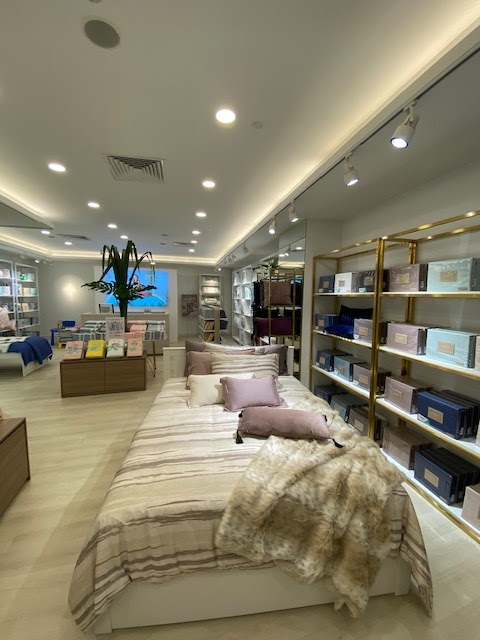 Interior view of KOMME, a home goods store, showcasing a beautifully styled bed with bedding and pillows.