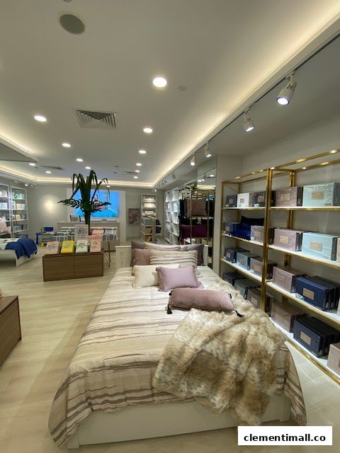 Interior view of KOMME, a home goods store, showcasing a beautifully styled bed with bedding and pillows.