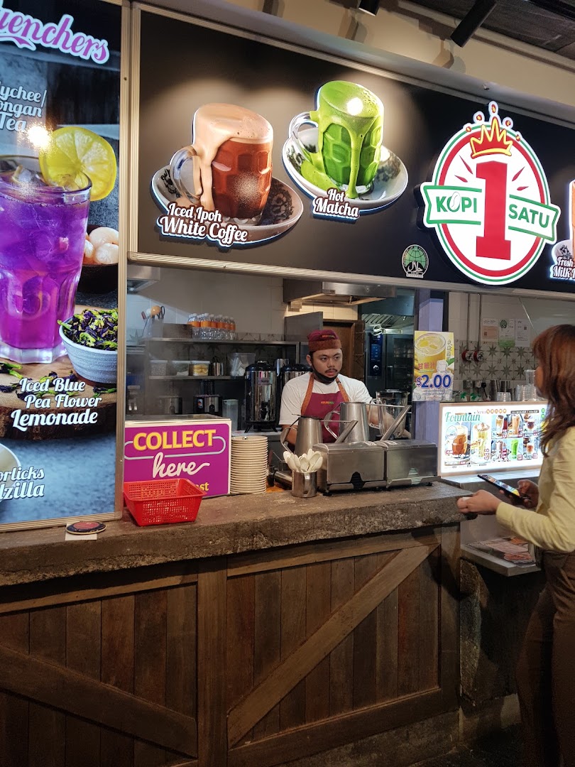 A staff member serves customers at the Kopi Satu counter, featuring vibrant drink displays.