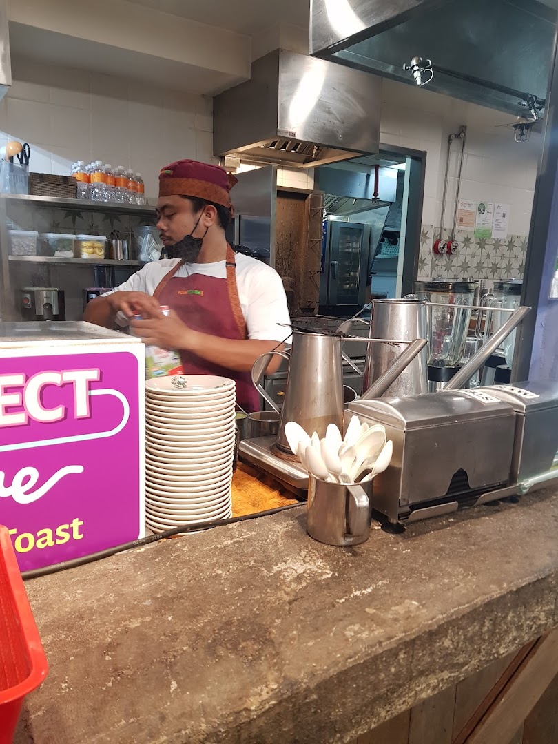 A staff member prepares drinks behind the counter in Kopi Satu's bustling kitchen.