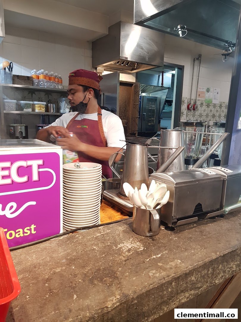 A staff member prepares drinks behind the counter in Kopi Satu's bustling kitchen.