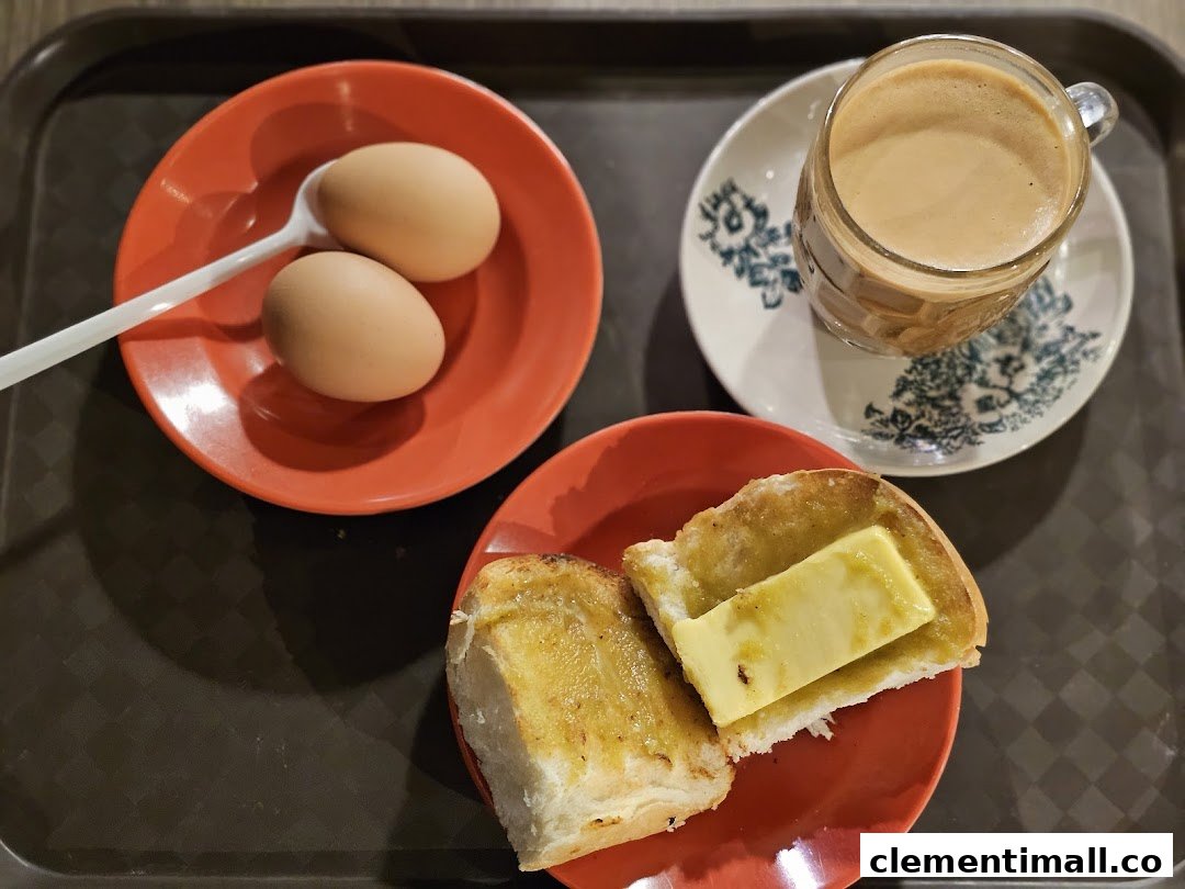 A classic breakfast set featuring soft-boiled eggs, kaya toast with butter, and a cup of coffee.