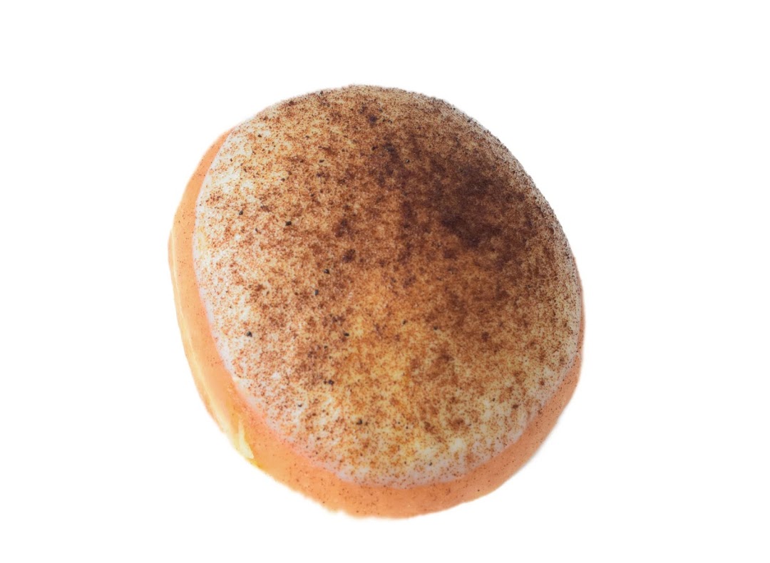 A single Krispy Kreme donut with light orange glaze and cinnamon sugar topping on a white background.