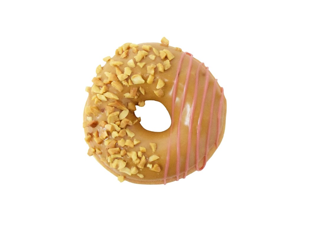A delicious Krispy Kreme donut with peanut topping and pink icing drizzle on a white background.