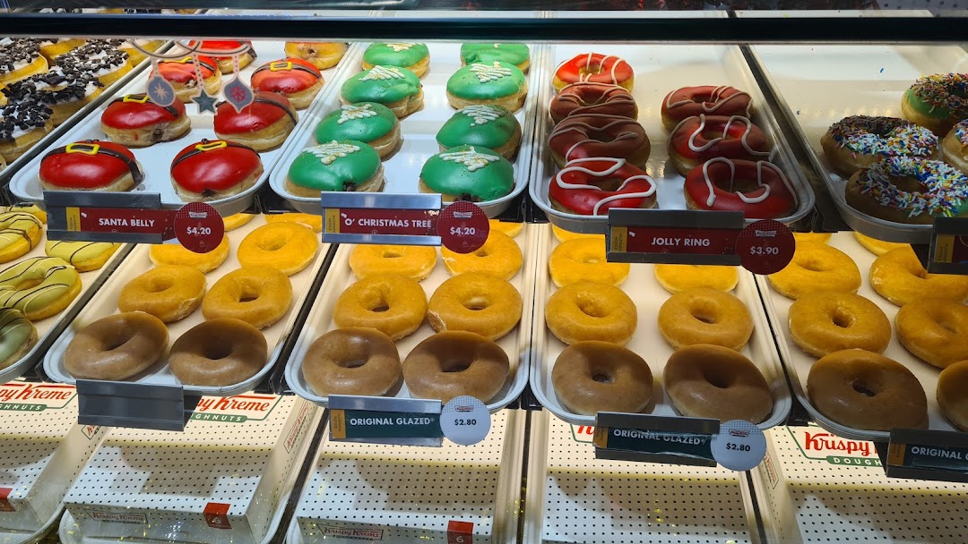 A vibrant display of Krispy Kreme donuts, including festive seasonal and classic glazed varieties.