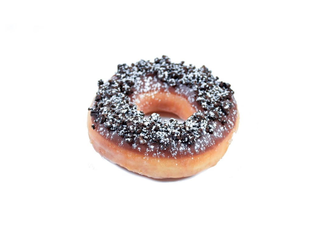 A delicious Krispy Kreme donut topped with chocolate glaze, cookie crumbs, and powdered sugar.