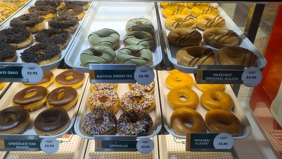 A vibrant display case showcasing a variety of Krispy Kreme donuts with different glazes and toppings.