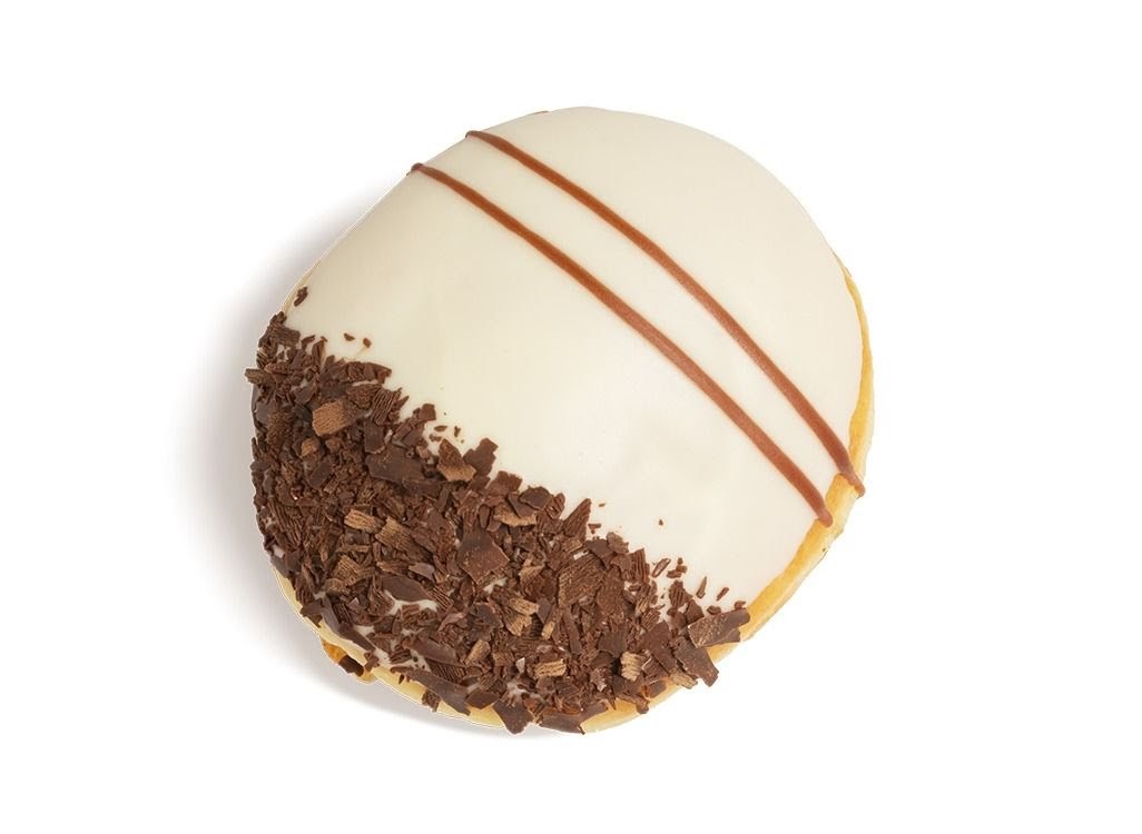 A delicious Krispy Kreme donut with white icing, chocolate shavings, and brown stripes.