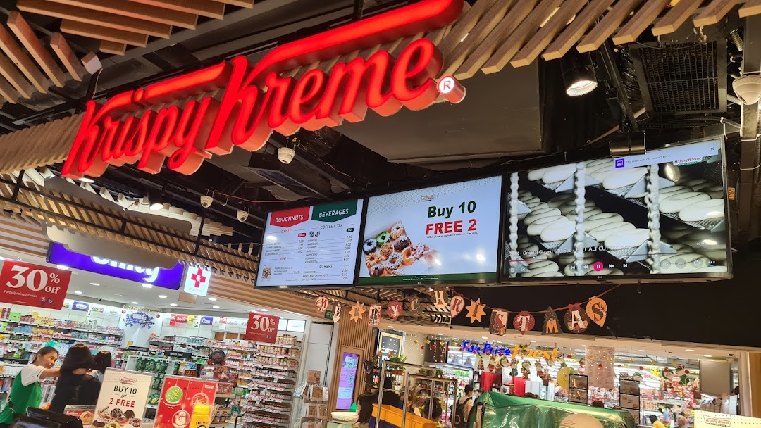 Interior view of Krispy Kreme with prominent signage and digital menu boards displaying doughnuts and beverages.