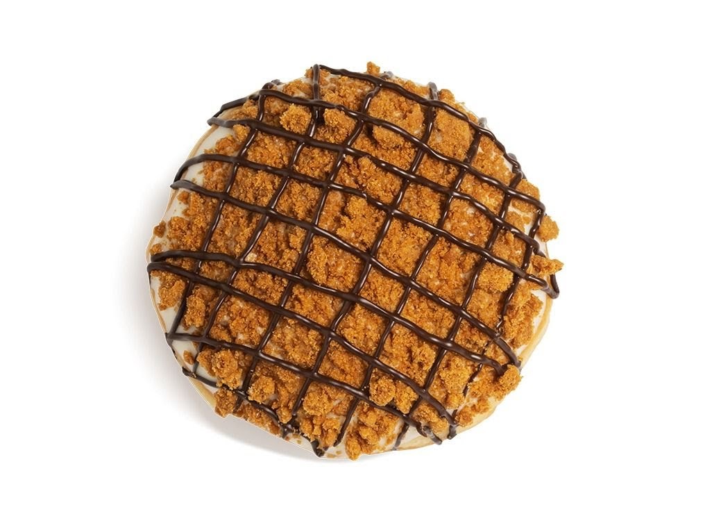 A delicious Krispy Kreme donut topped with cookie crumbs and chocolate drizzle.