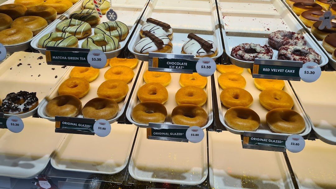 A vibrant display of various Krispy Kreme donuts, showcasing different flavors and prices.