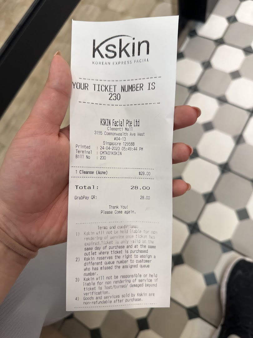 A hand holds a Kskin Korean Express Facial service ticket with details of a cleanse service.