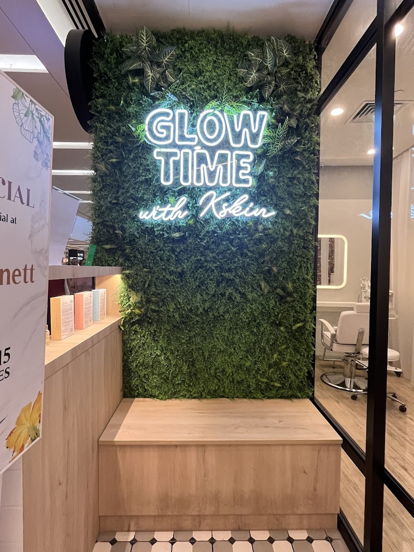 A vibrant green wall with a 'Glow Time with Kskin' neon sign and a wooden bench inside the facial shop.