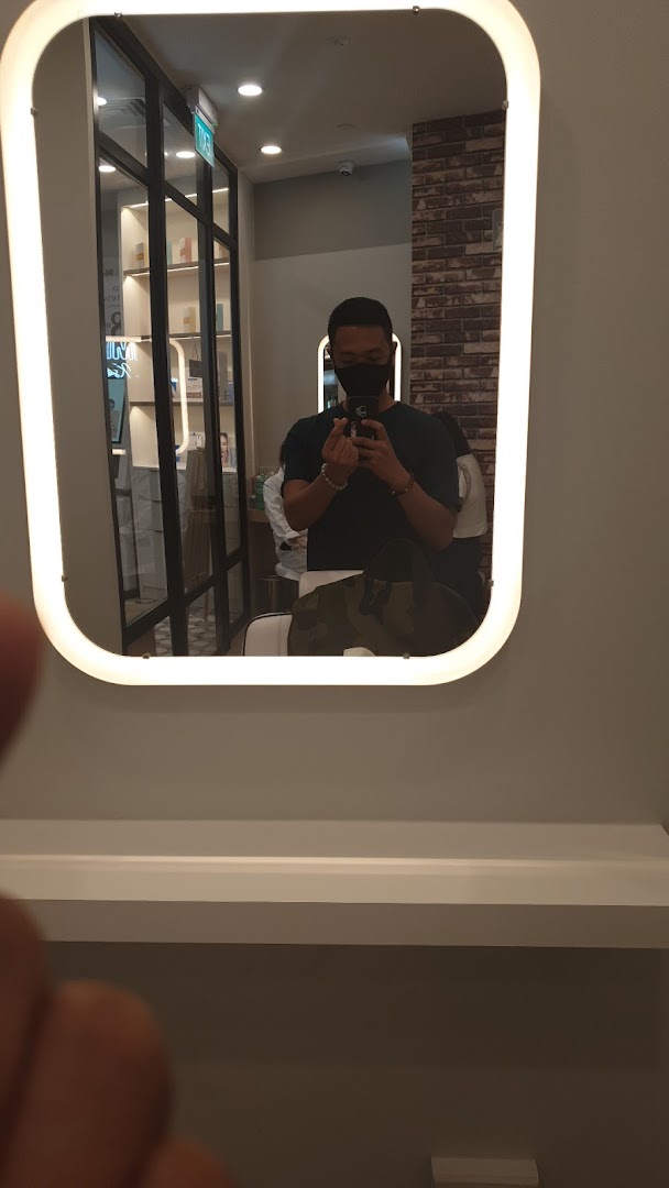 A person taking a mirror selfie inside Kskin, showing the modern interior with product displays.
