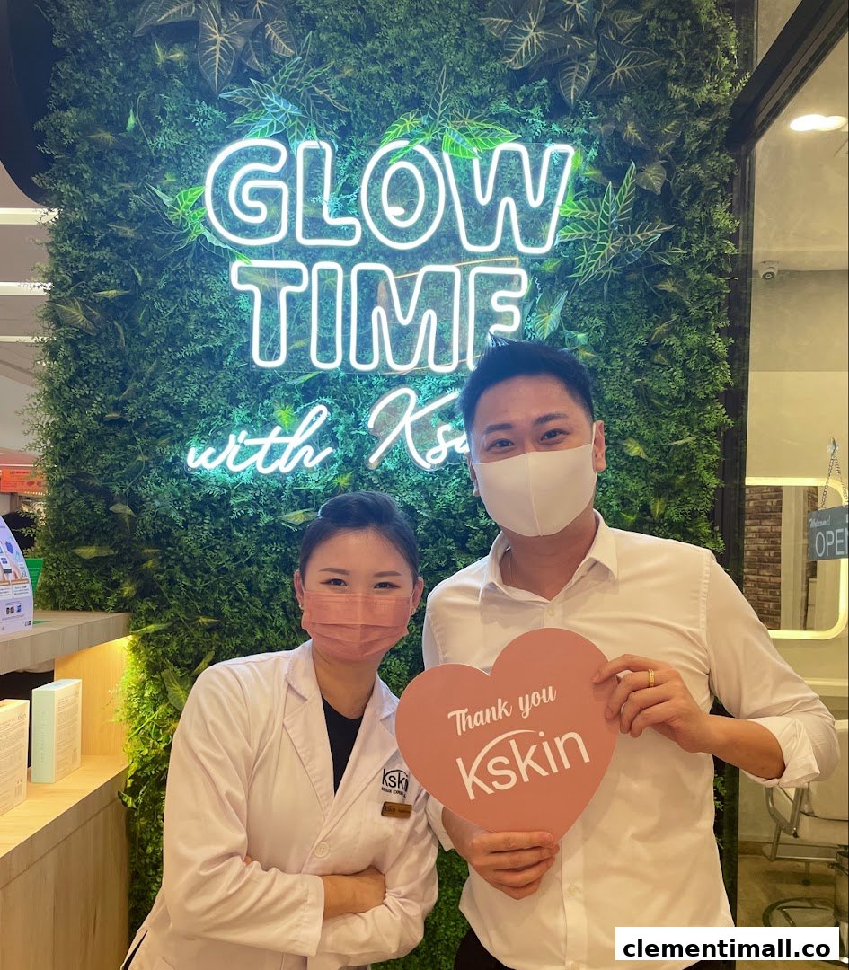 Two Kskin staff members smiling in front of a 'Glow Time' neon sign on a green wall.