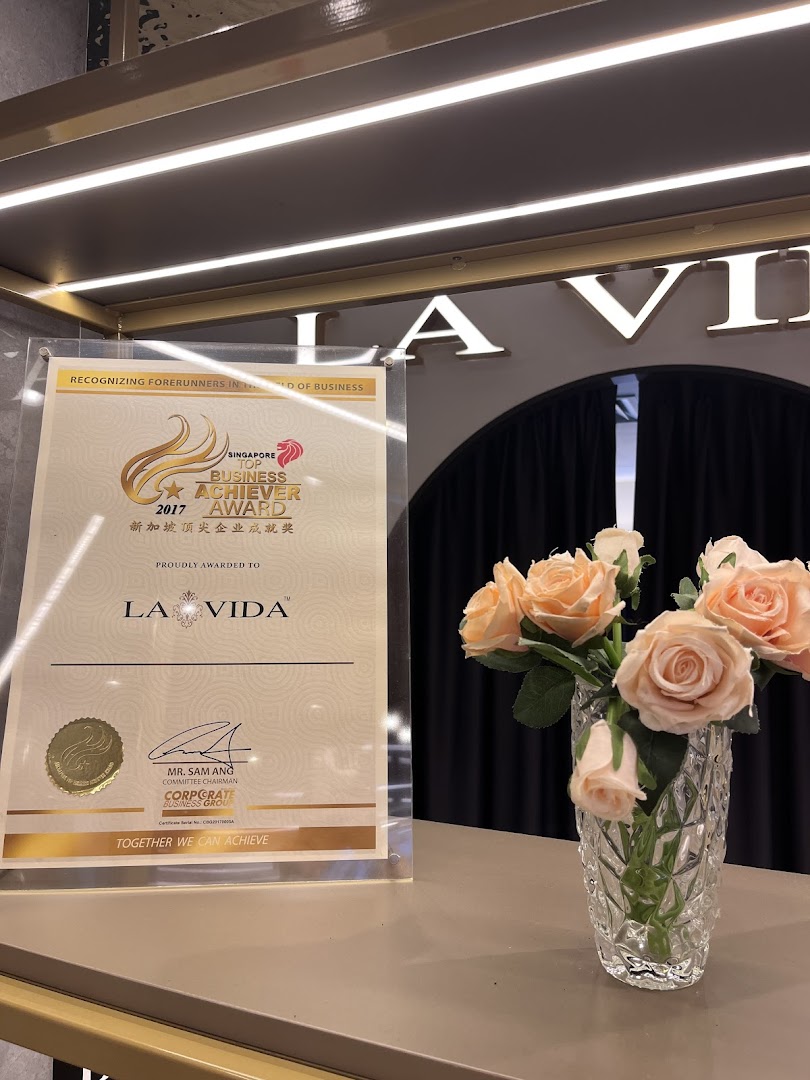 An award certificate for La Vida and a vase of flowers displayed on a counter.