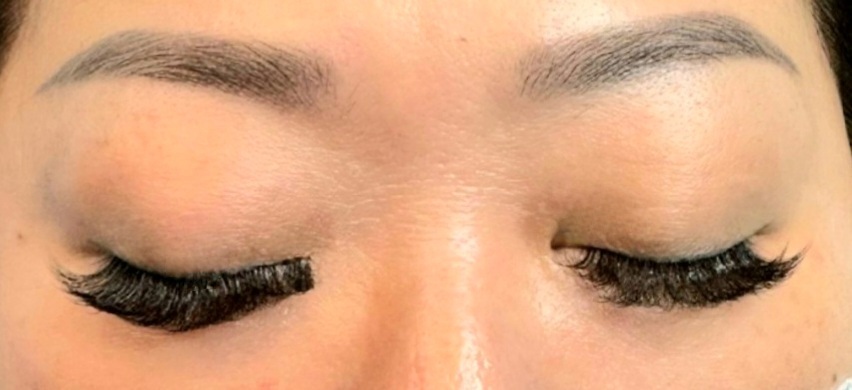 Close-up of a person's eyes showcasing eyelash extensions, with one eye partially done.