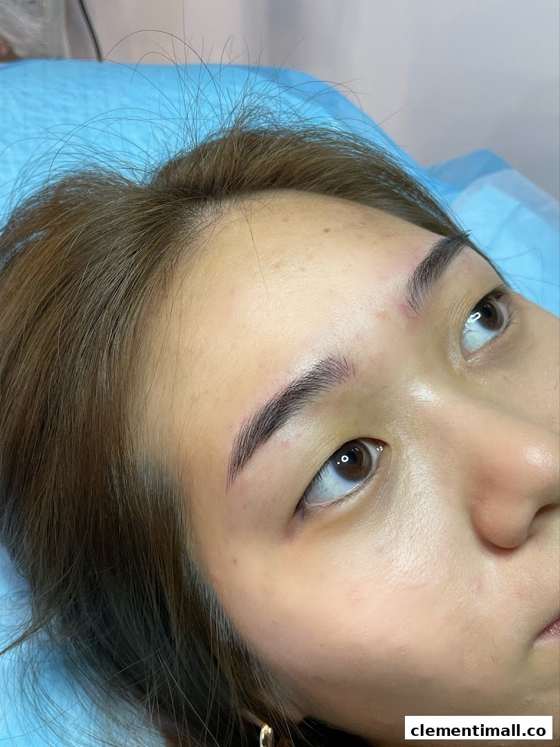 Close-up of a person's face showcasing freshly done eyebrows on a treatment bed.