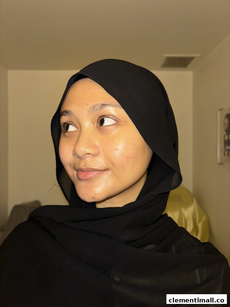 A young woman in a black hijab looking away, with a subtle smile.