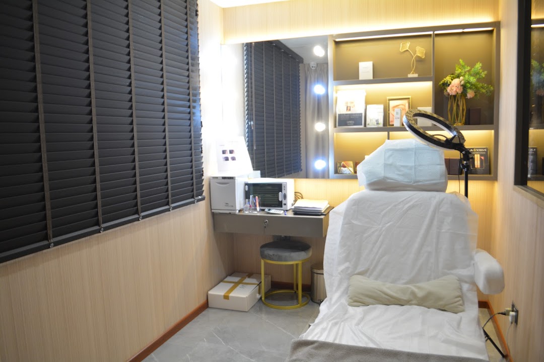 A modern and well-lit beauty treatment room featuring a comfortable chair, vanity, and display shelves.