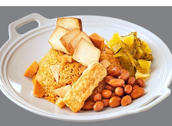 A hearty plate featuring rice, peanuts, pickled vegetables, and fried tofu/bread on a white dish.