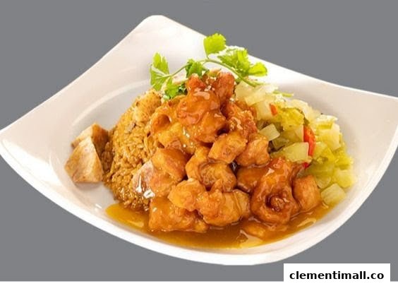 A delicious plate featuring golden fried chicken in sauce, fried rice, and pickled vegetables.