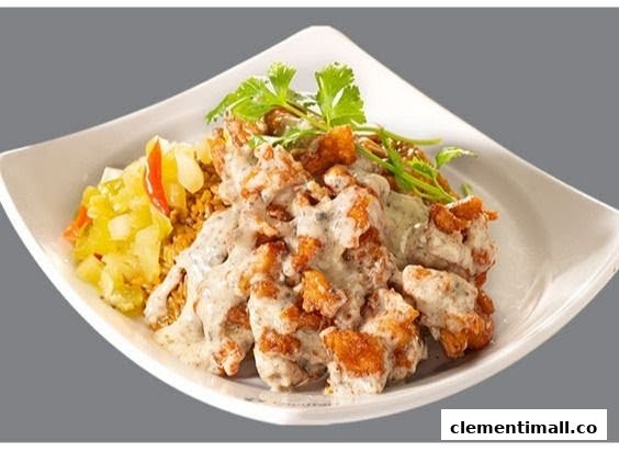 A plate of crispy fried chicken or pork pieces coated in a creamy sauce, served with rice and pickled vegetables.