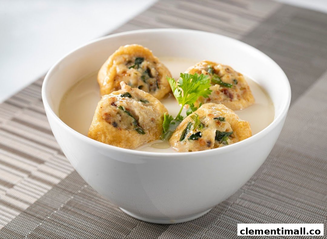 A white bowl filled with creamy soup and four pieces of stuffed fried tofu, garnished with cilantro.