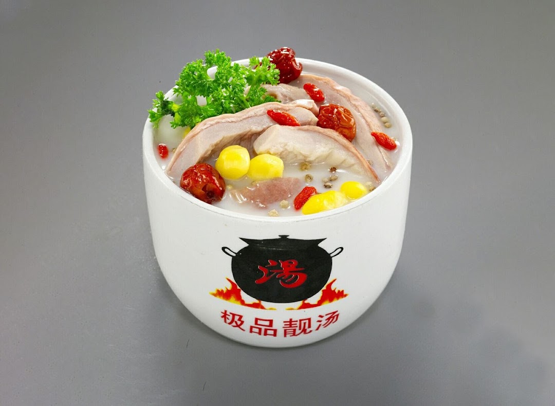 A white bowl filled with traditional Chinese herbal soup, garnished with herbs, red dates, and ginkgo nuts.