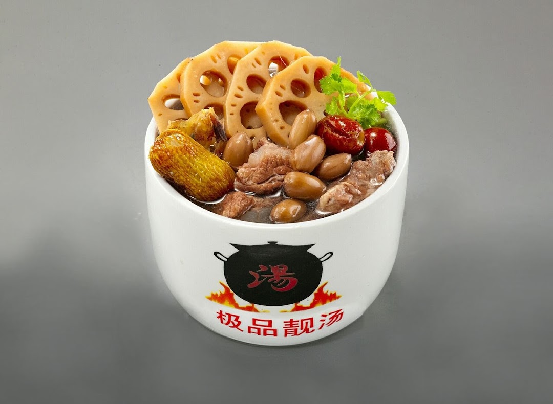 A close-up of a white bowl filled with traditional Chinese herbal soup, featuring lotus root, peanuts, and meat.