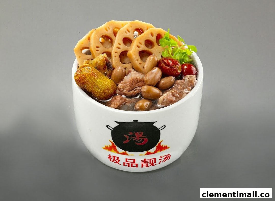 A close-up of a white bowl filled with traditional Chinese herbal soup, featuring lotus root, peanuts, and meat.