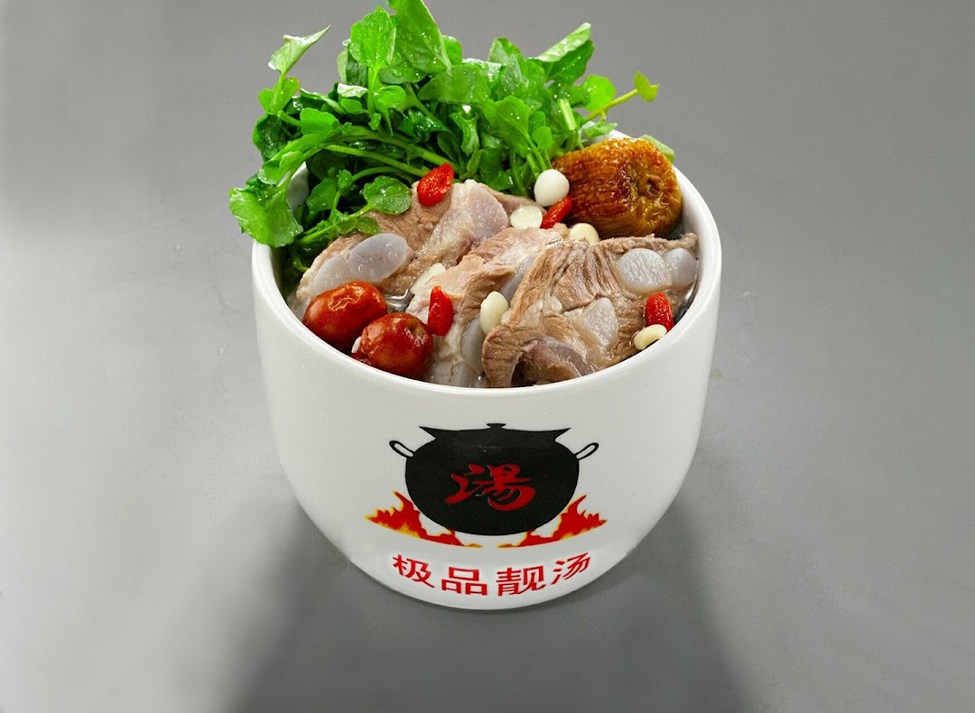 A white bowl filled with herbal soup, pork ribs, red dates, goji berries, and fresh greens.