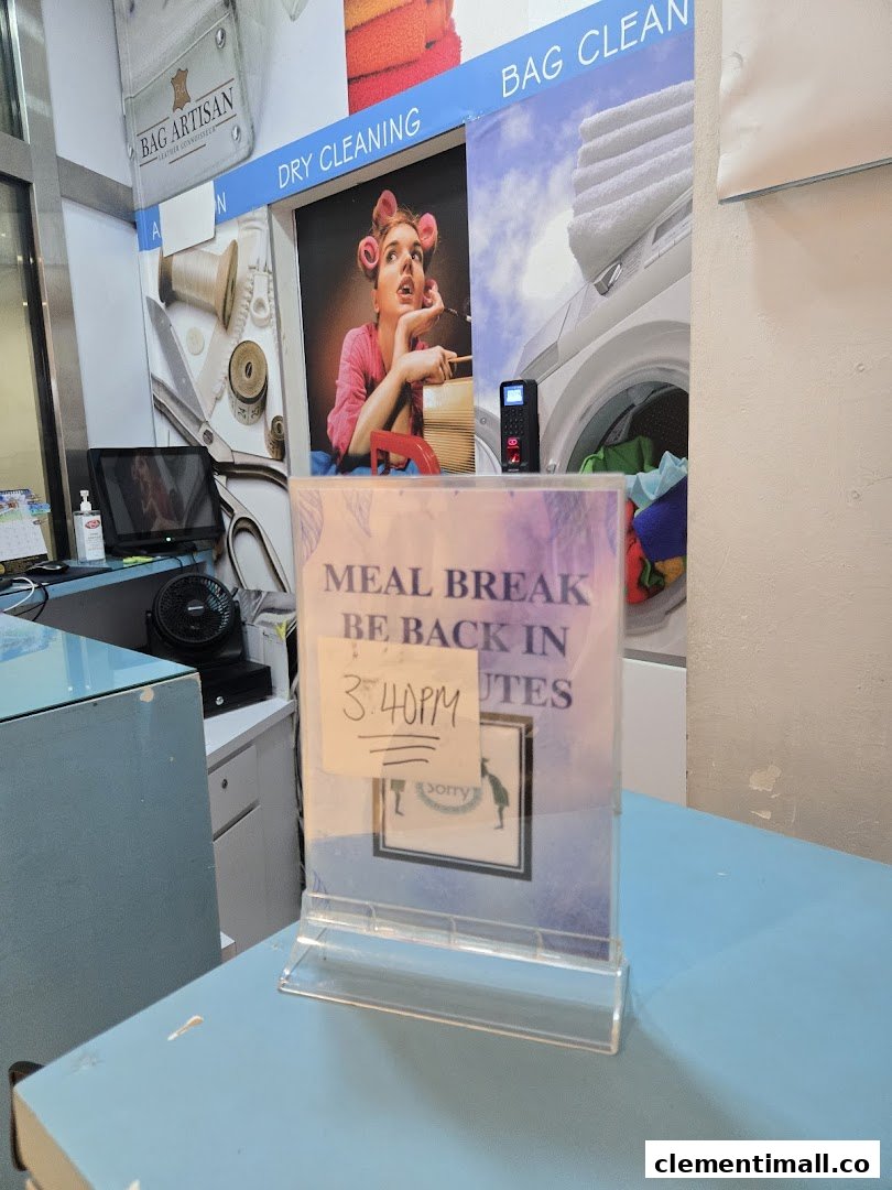 Interior view of Laundry Club's counter, featuring service signs and a temporary 'Meal Break' notice.