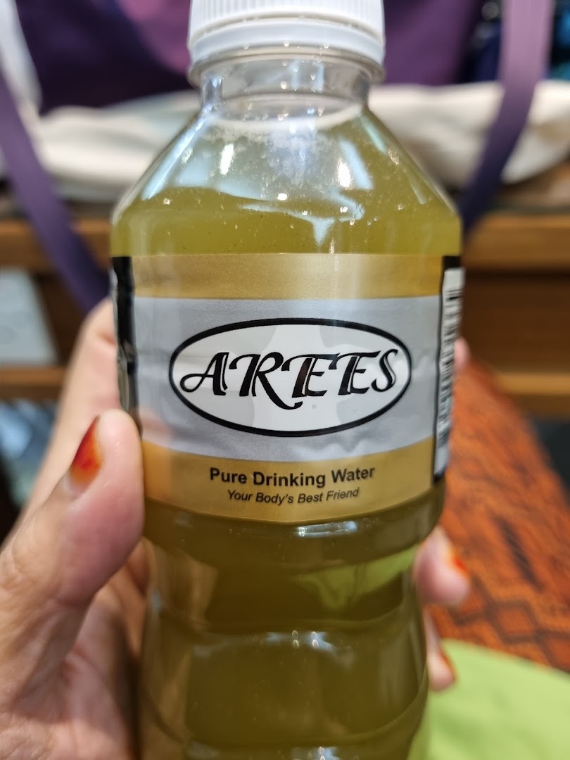 Close-up of a hand holding a bottle of ARTES Pure Drinking Water.