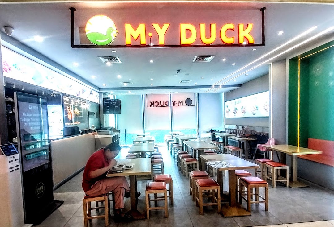 Interior view of M.Y Duck restaurant with seating, a counter, and a customer dining.